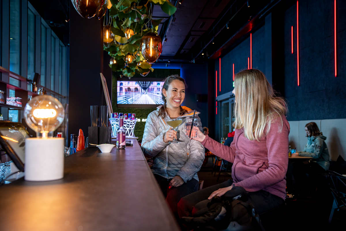 Zwei Frauen stossen an der Theke der e-tron energy bar mit Cocktails an.