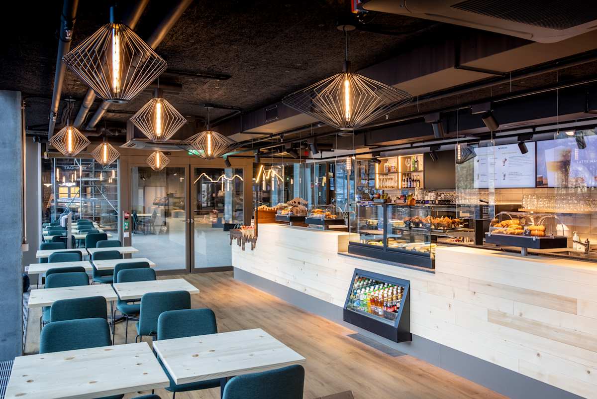 Modernes Bistro im Grindelwald Terminal mit Sitzbereich, Verkaufstheke und Vitrinen mit Snacks und Backwaren.