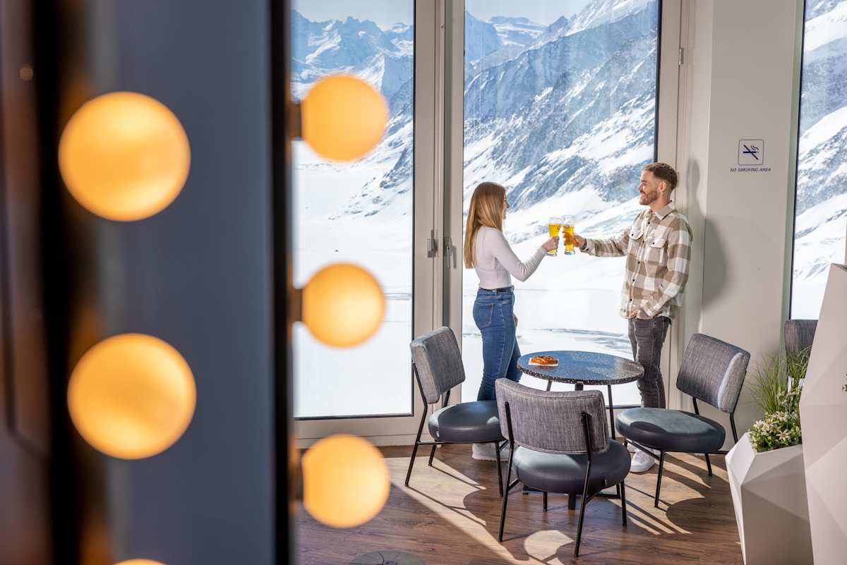 Two people toasting by the windows of the Pikantus Lounge